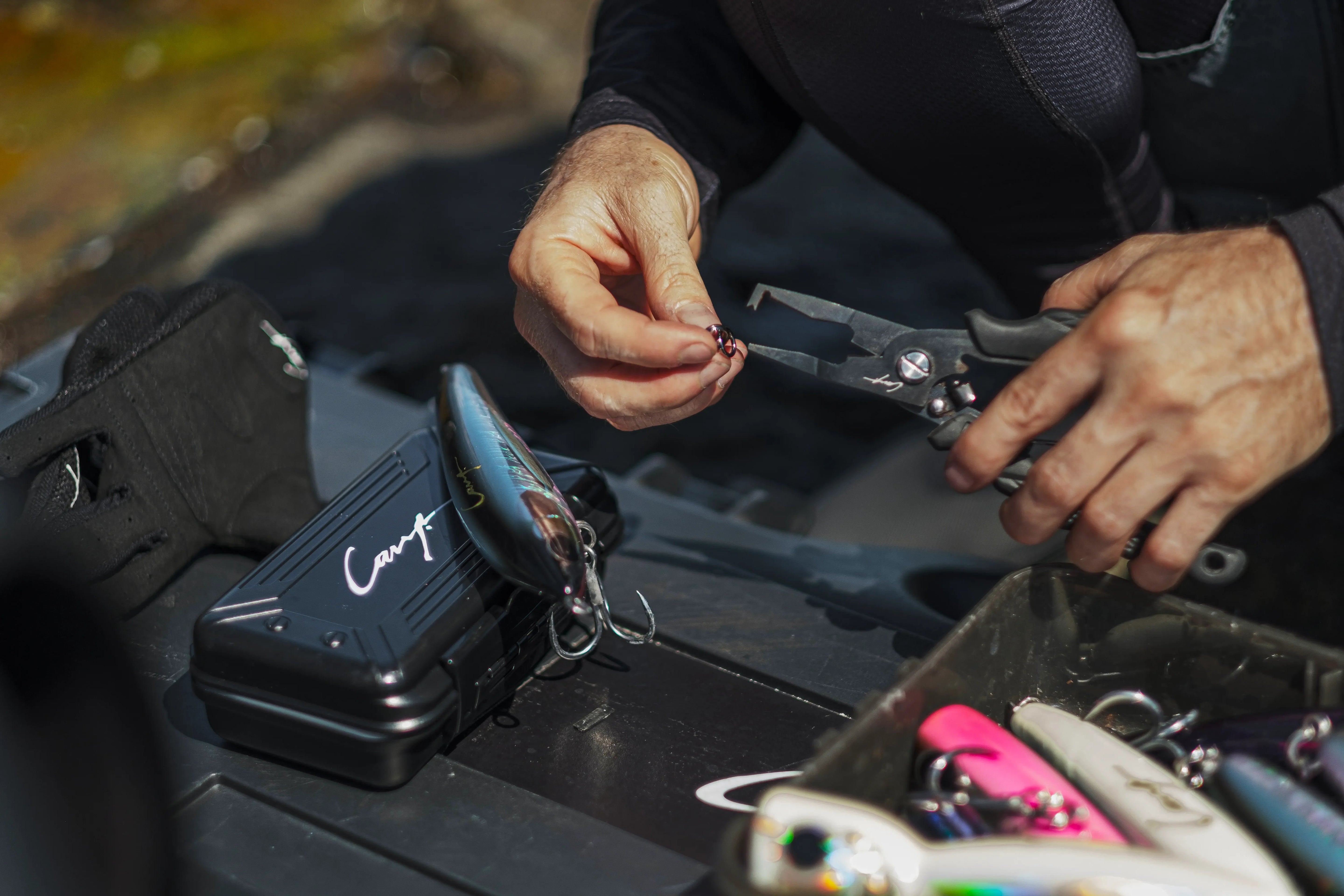 Angler using Cavy Fishing pliers to attach split ring to lure, showing durable saltwater-ready fishing tools tested in real coastal conditions.