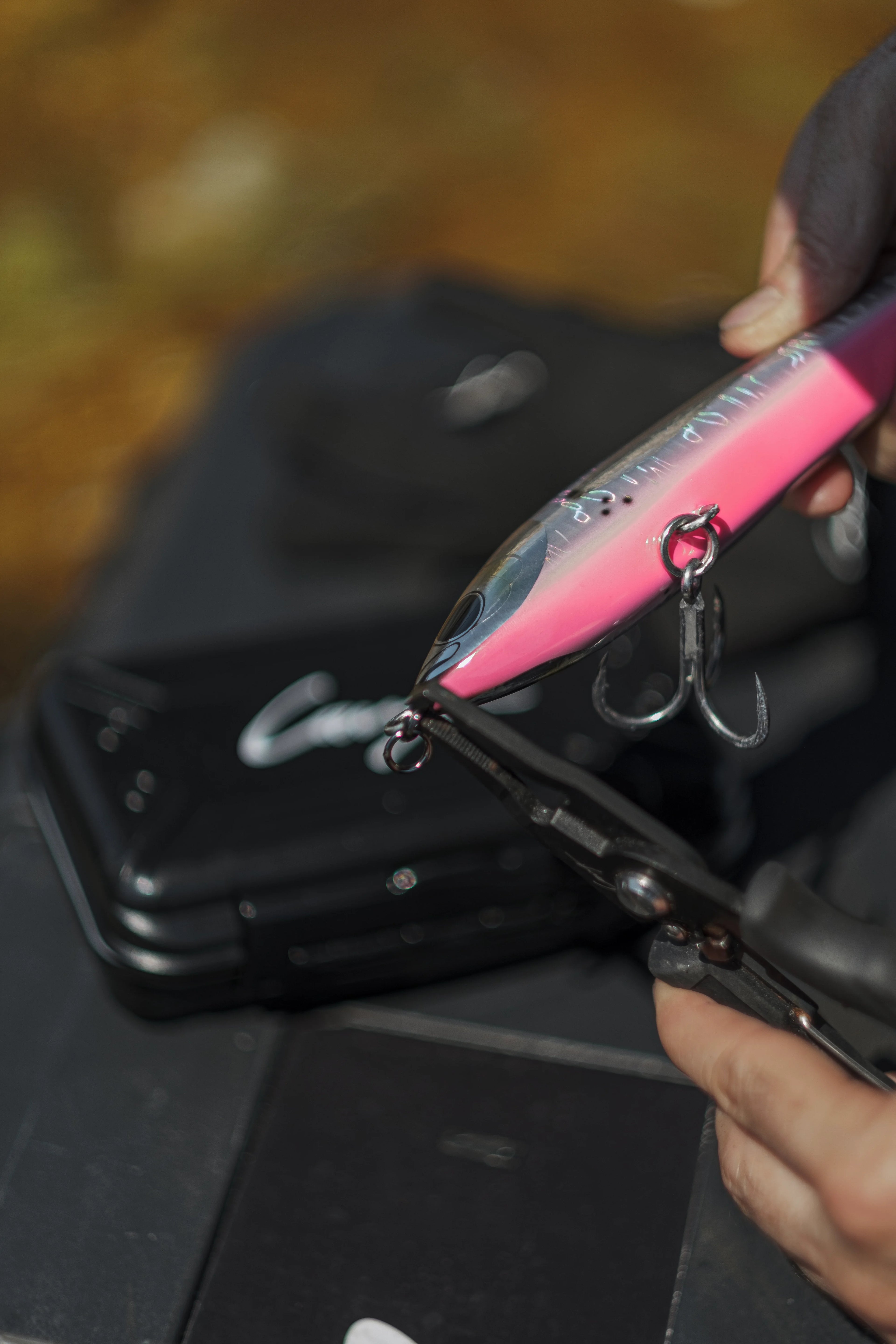 Angler using fishing pliers to rig a lure.