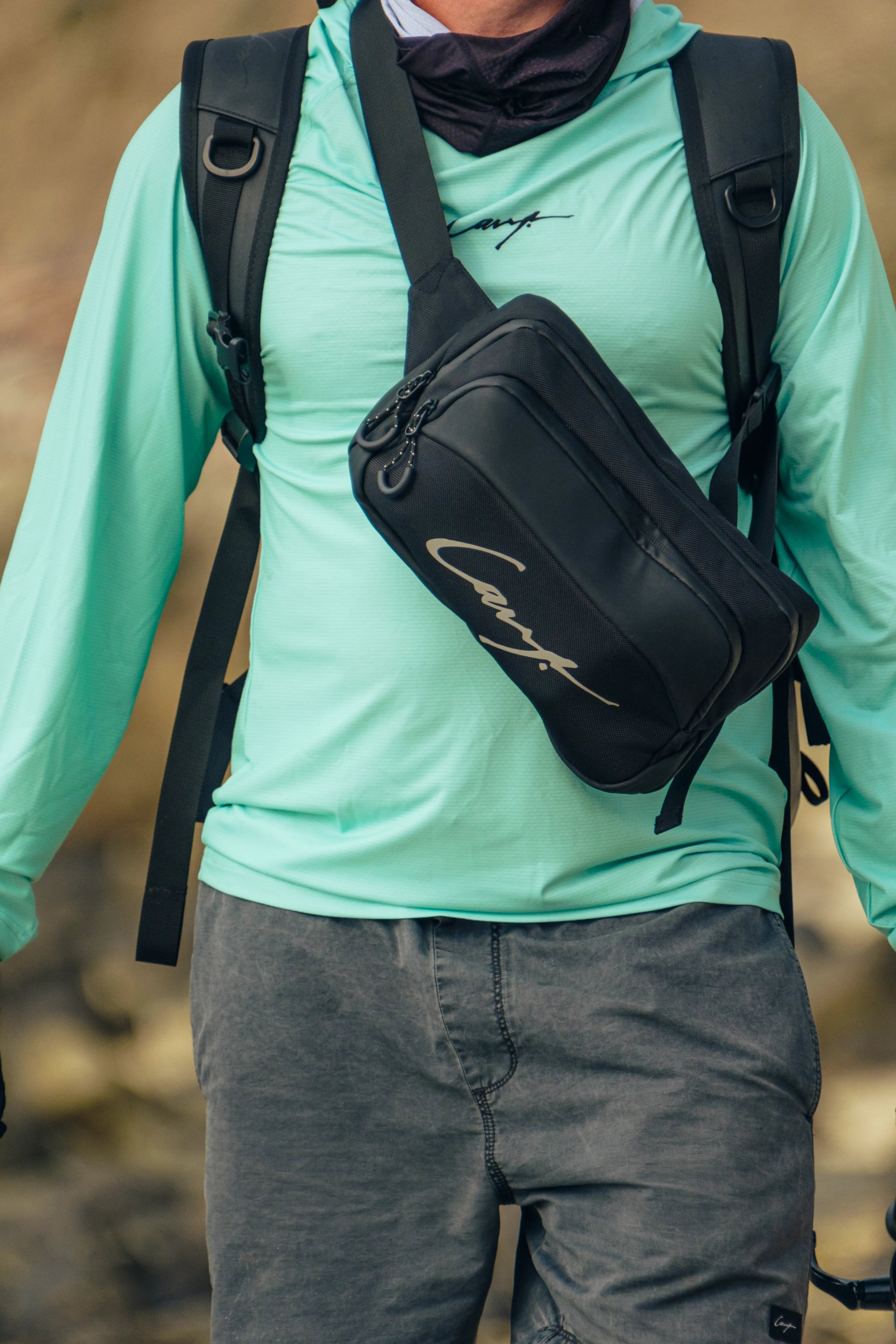 Close-up of Cavy Fishing waterproof sling bag and UV shirt worn by an angler on the coast