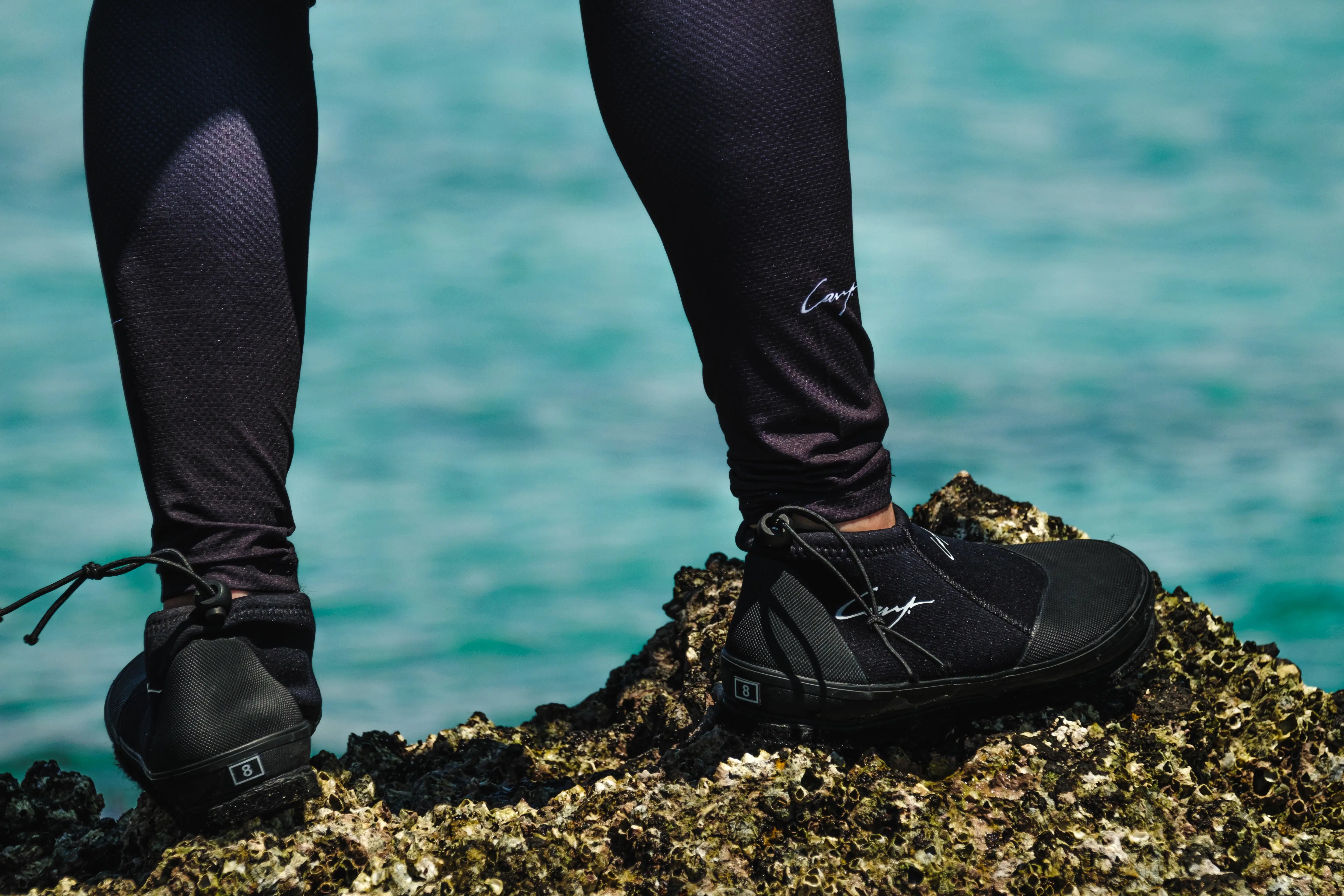 Angler standing on reef rocks wearing Cavy Rock Hopper fishing shoes, showing saltwater-ready footwear with strong grip for slippery coastal terrain.